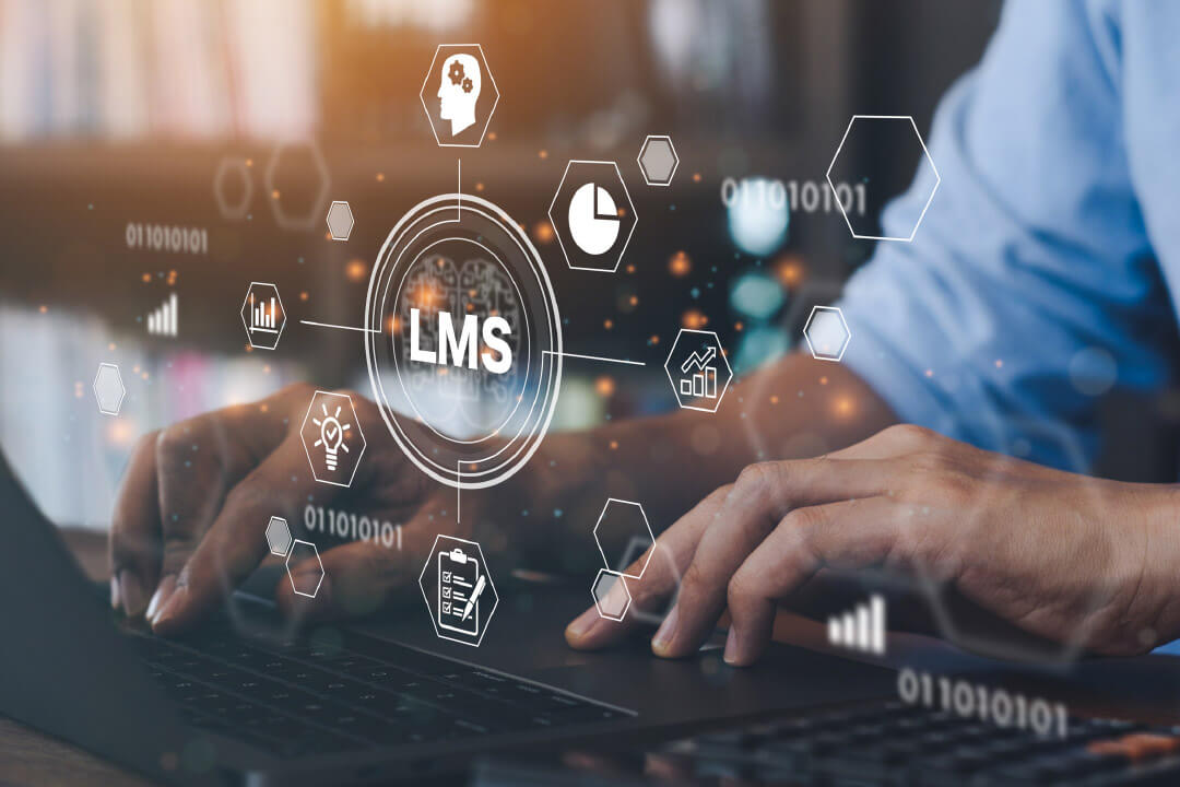 LMS A focus on a person's hands typing at a laptop with graphic elements representing a learning management system float in front of the screen