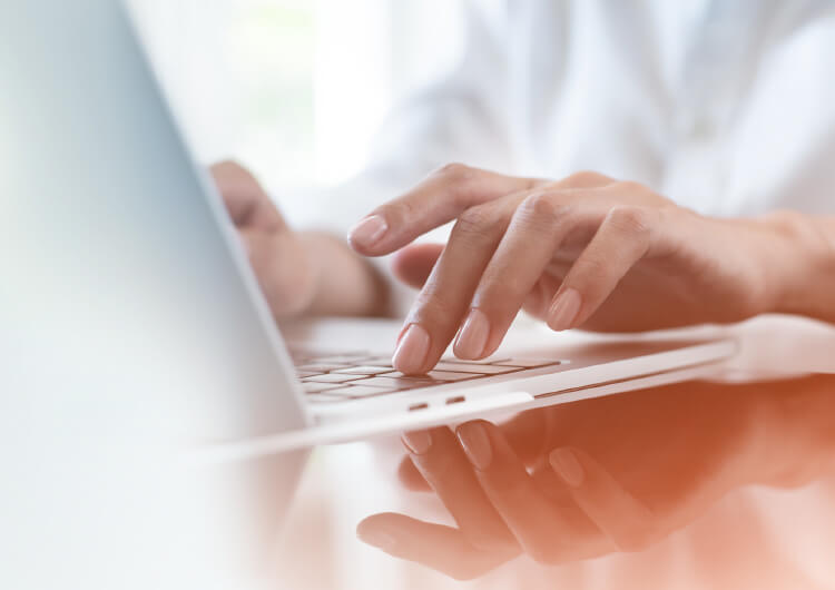 Learning Solutions - Learning Management System A focus on a person's hands typing at a laptop